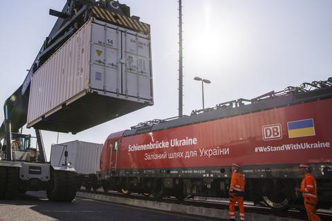 Arbeiter verladen Container auf einen Zug der DB-Schienenbrücke Ukraine vor der Abfahrt mit Hilfsgütern aus Berlin. Foto: Carsten Koall/dpa