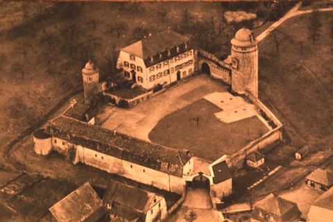 Blick von oben auf das imposante Schlossareal mit weitläufiger Parkanlage in einer Luftaufnahme aus den 1950er Jahren. Links sind der abgebrochene Turm zu sehen und der Wehrgraben, der rund ums Schloss führt. 