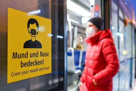 Eine Frau betritt mit FFP2-Maske eine Trambahn in München.