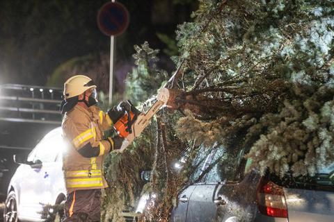 Ein Feuerwehrmann zersägt einen Baum der beim Sturm Antonia auf ein Auto gestürzt ist. Das Sturmtief «Antonia» fegt mit hoher Geschwindigkeit über Baden-Württemberg hinweg.  Foto: Simon Adomat/VMD-Images /dpa