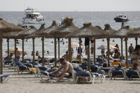 Gäste liegen am Strand von Paguera auf Mallorca oder gehen schwimmen.  Foto: Clara Margais