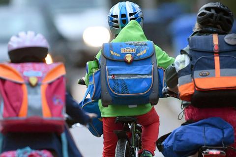 Kinder sind auf einer Straße mit dem Fahrrad unterwegs zur Schule.  Foto: Ralf Hirschberger/dpa