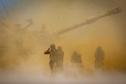 Israelische Soldaten stehen in aufgewirbeltem Staub, nachdem ein Artilleriegeschütz auf Ziele im Gazastreifen gefeuert hat. Foto: dpa