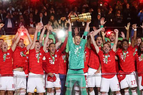 Torwart Manuel Neuer von Bayern reckt den Pokal in die Höhe während seine Mitspieler den Pokalsieg bejubeln. Foto: dpa