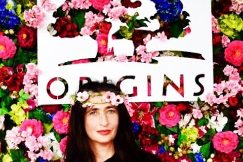 Mit Blumen im Haar vor der schönen Fotowand von Origins. Foto: Anja Kossiwakis