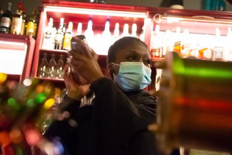 Eine Barkeeperin mixt einen Drink und trägt bei der Arbeit einen Mund-Nase-Schutz. Symbolfoto: dpa