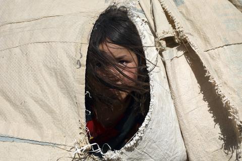 Ein afghanisches Mädchen, das aufgrund von von Kämpfen zwischen den Taliban und afghanischen Sicherheitskräften aus ihrer Heimat geflohen ist, blickt aus einem Zelt heraus. Tausende Menschen fliehen aus dem Norden des Landes, aus Angst vor der Taliban.  Foto: Rahmat Gul/AP/dpa