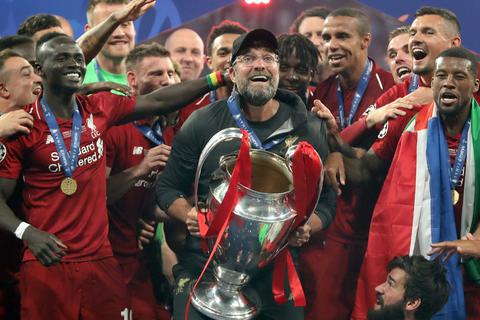 Liverpool-Coach Jürgen Klopp (Mitte) jubelt mit dem Champions League-Pokal über den Finalsieg 2019. 